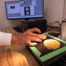 A person places a petri dish on a table next to a computer